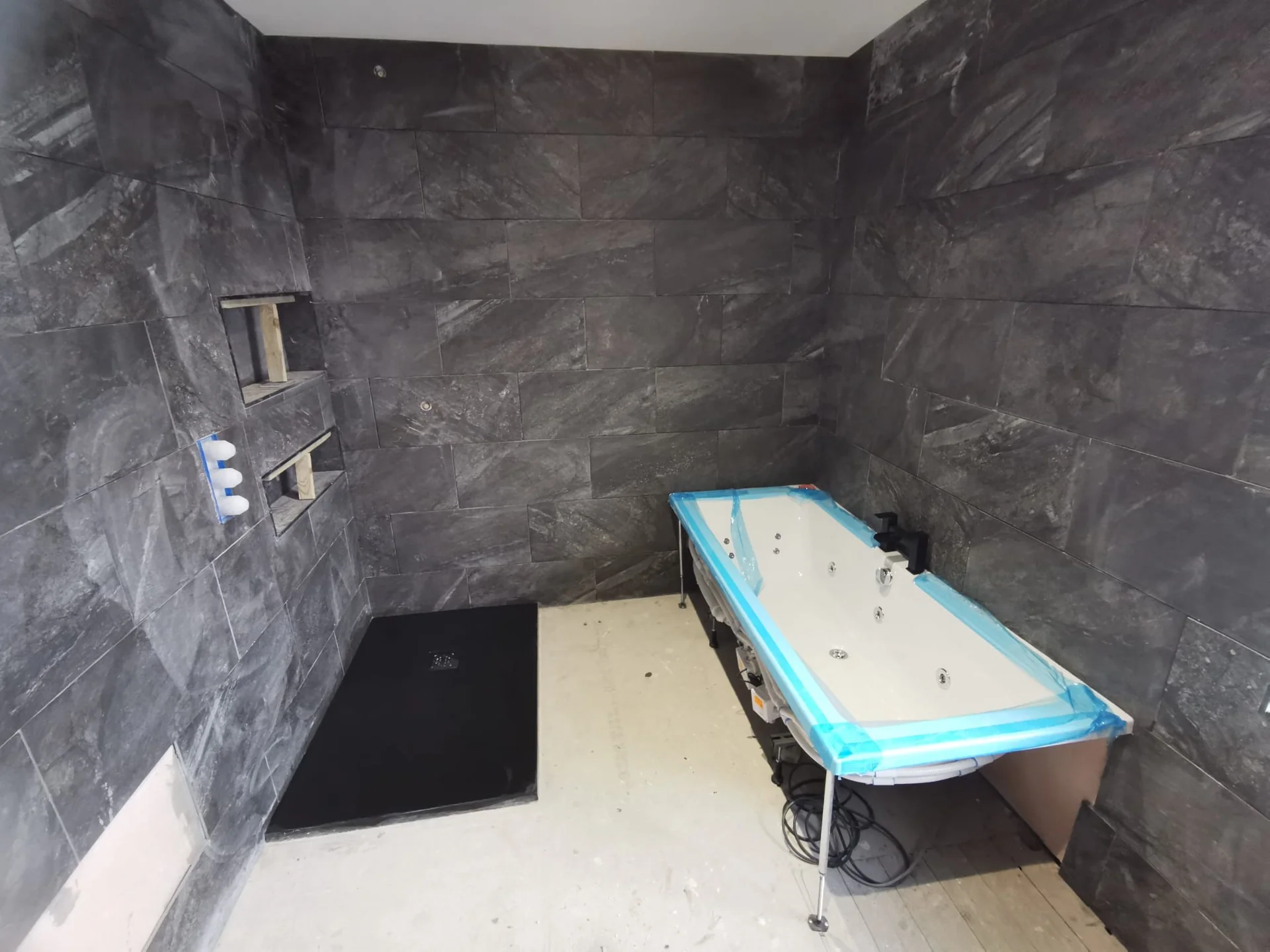 Bathroom tiling in progress around the bath