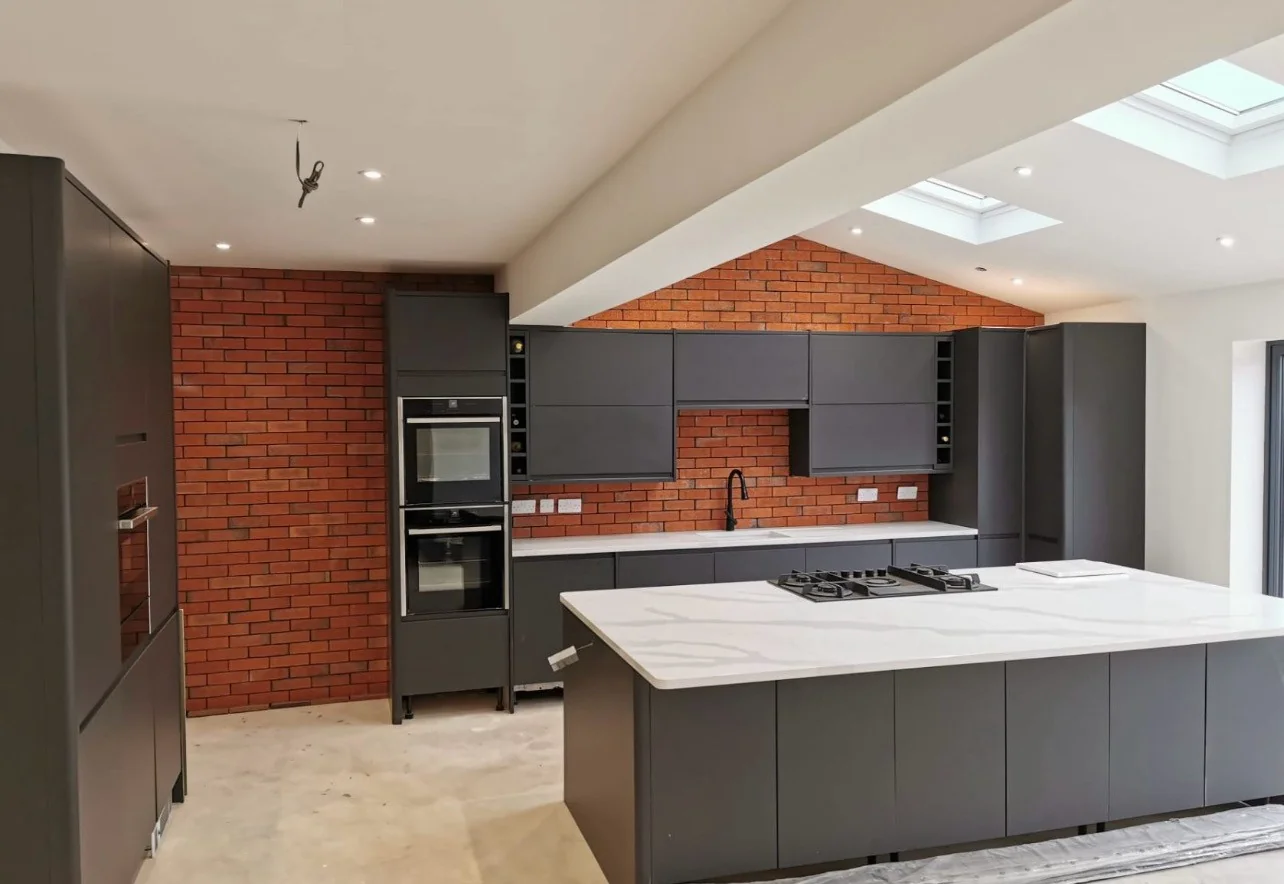 Charcoal kitchen cabinetry, white island and exposed brick wall